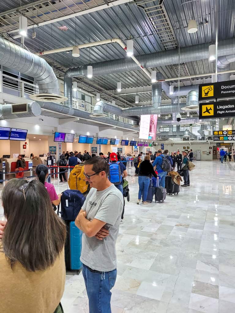 The departures hall at Queretaro Airport will travellers waiting in lines leading to various airline check in desks.