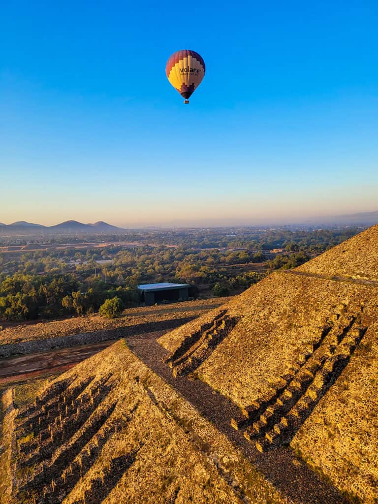 A view of a hot air balloon floating over the side of the pyramid at Teotihuacan near Mexico City.