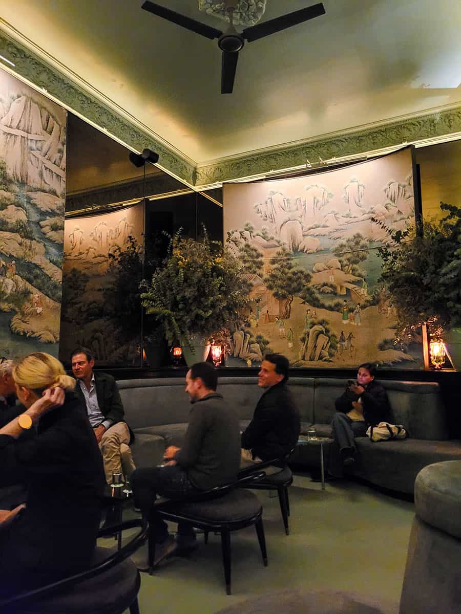 Patrons chat in Salon Rosetta with high ceilings and ornate art on the walls.