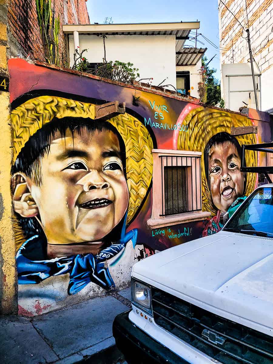 Street art in San Miguel de Allende of two smiling Mexican boys wearing straw hats.