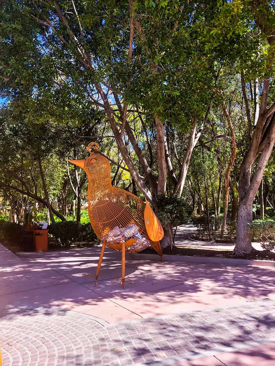 A large, orange bird sculpture that is also a recycling project to collect recyclable materials at Parque Benito Juarez, San Miguel de Allende.