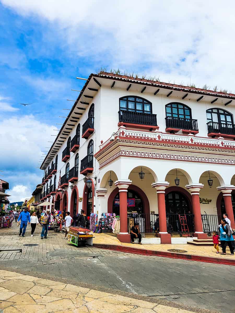 An ornate colonial building under a blue sky with Indigenous vendors in San Cristobal de las Casas.