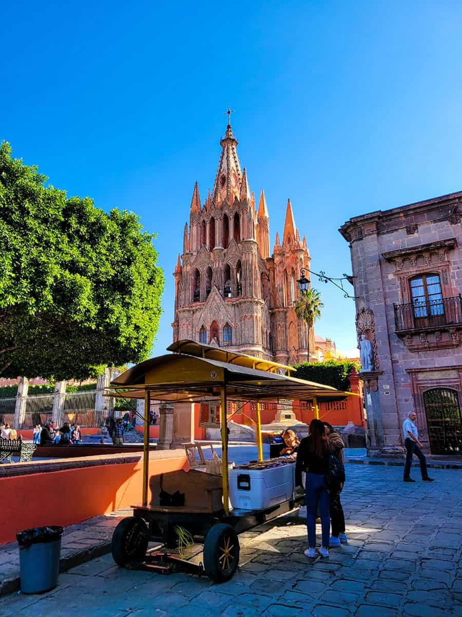 Two women stand in at an ice cream vendor in front of the Parroquia de San Miguel Arcángel in San Miguel de Allende.