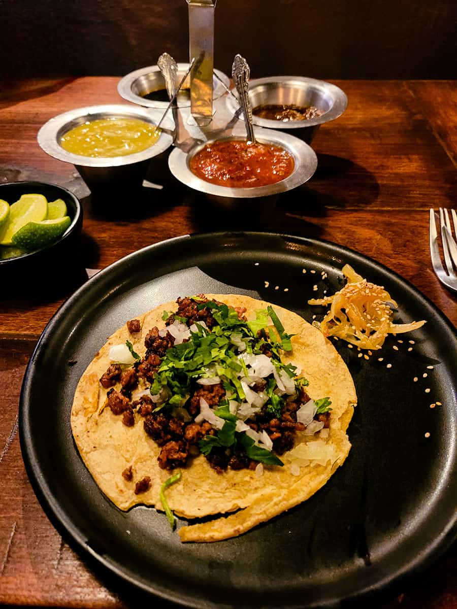 A taco topped with chopped onion and cilantro with a selection of salsas at a restaurant in San Miguel de Allende.