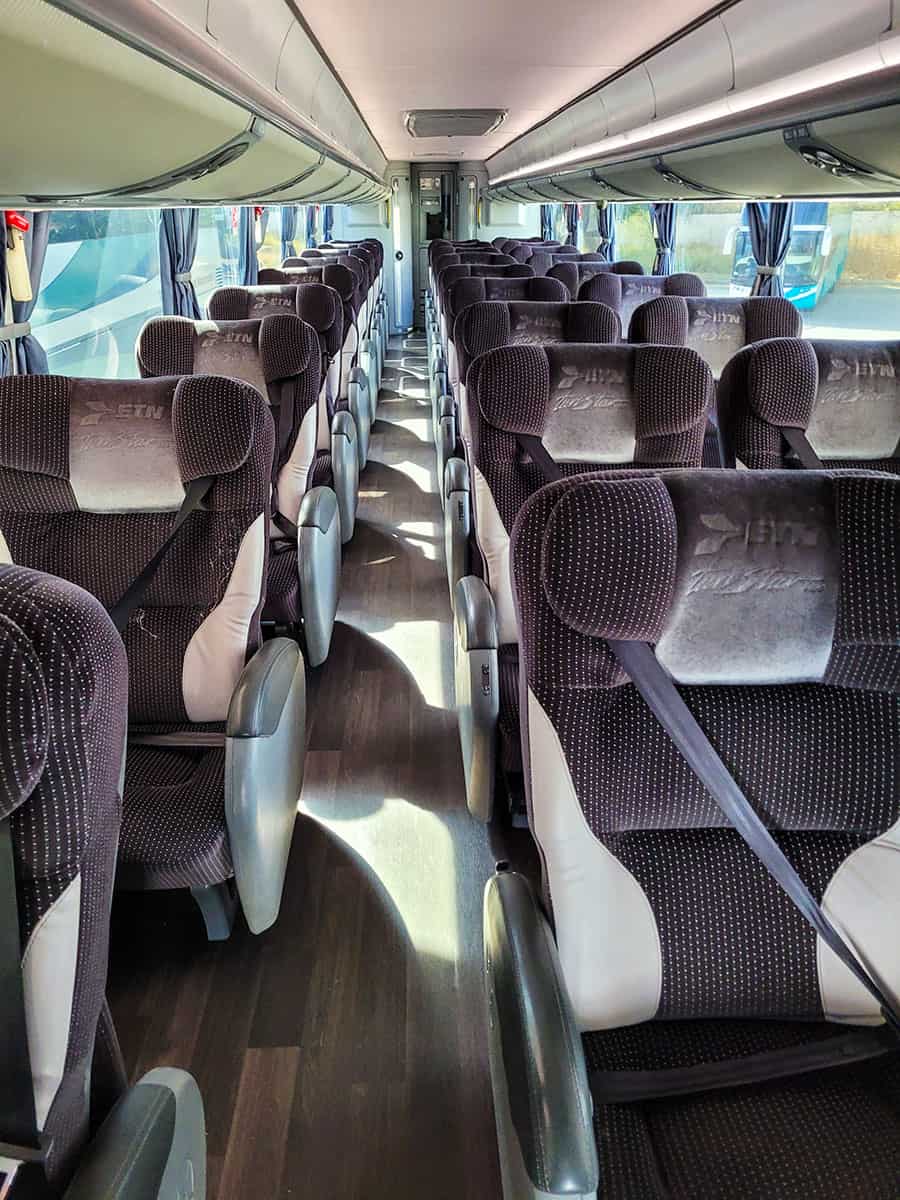 Inside of ETN first class luxury bus in Mexico with wood floors and fluffy cushioned seats.